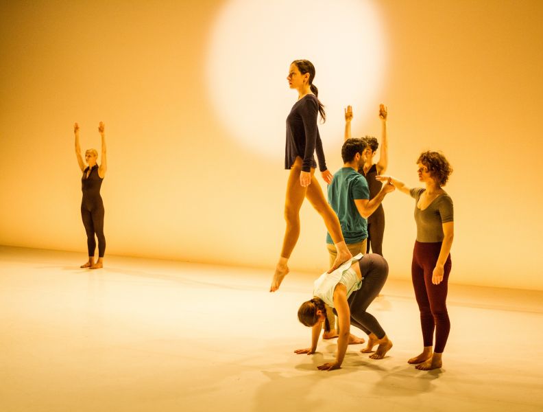 Dancers performing against a glowing cream backdrop.