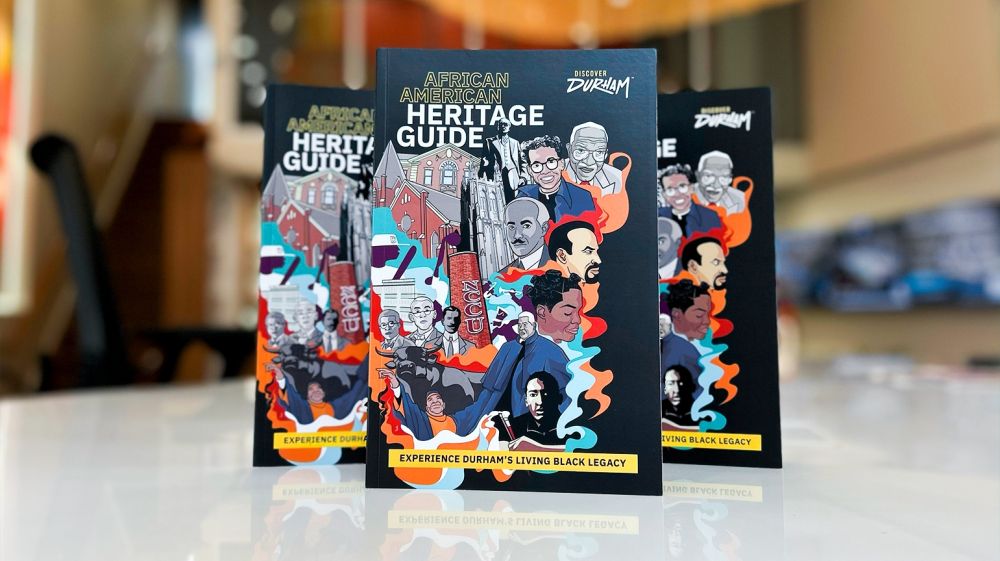 Three copies of Durham's African American Heritage Guide standing on a white table.