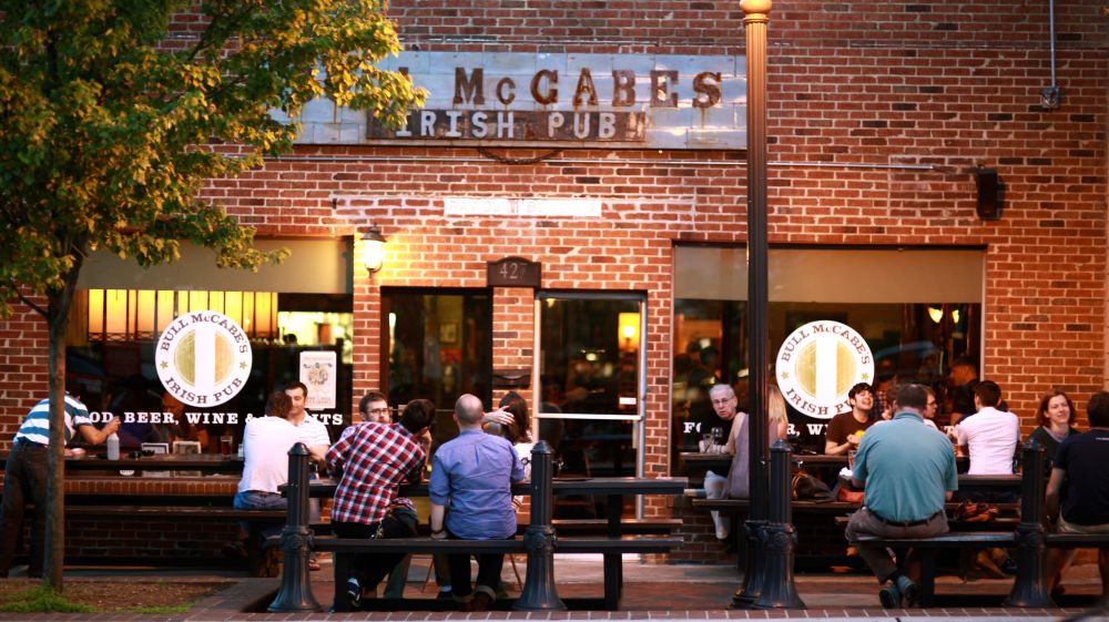 Patrons sit at tables at sunset outside of Bull McCabes in Durham, NC.