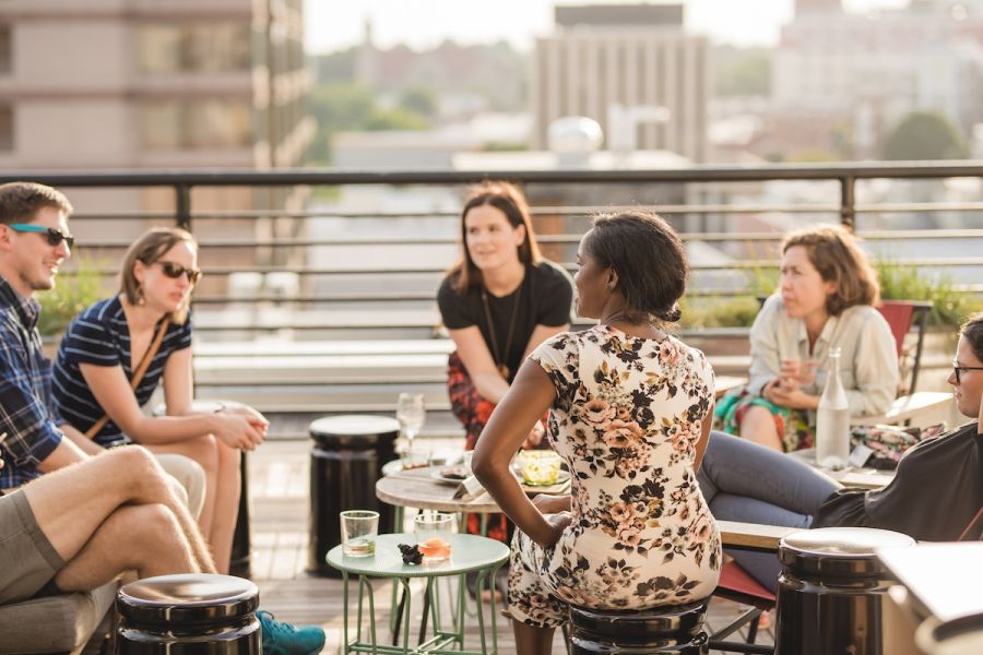 A group of friends hangs out on couches and seating at The Durham Hotel Roof.