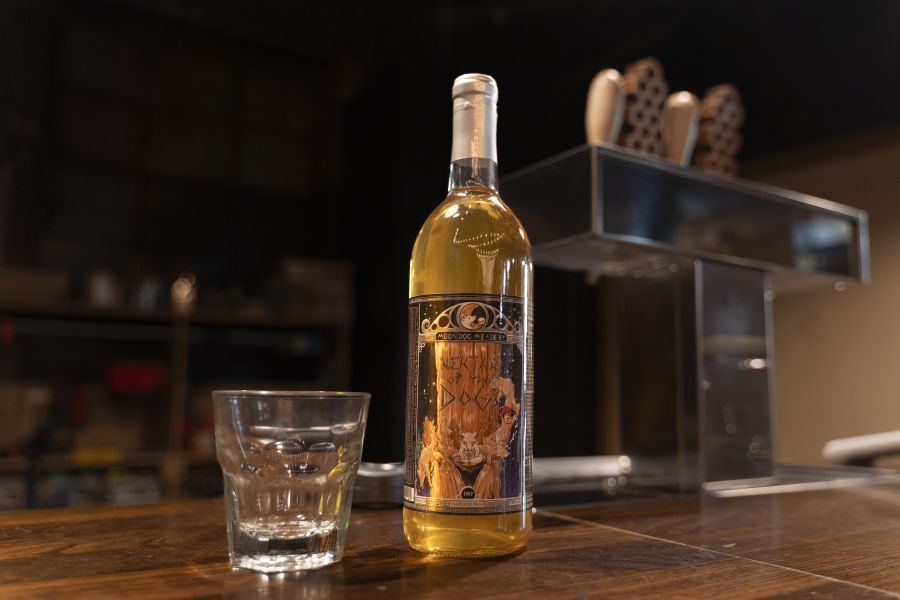 A bottle of mead sits on the bar next to a glass at Moon Dog Meadery