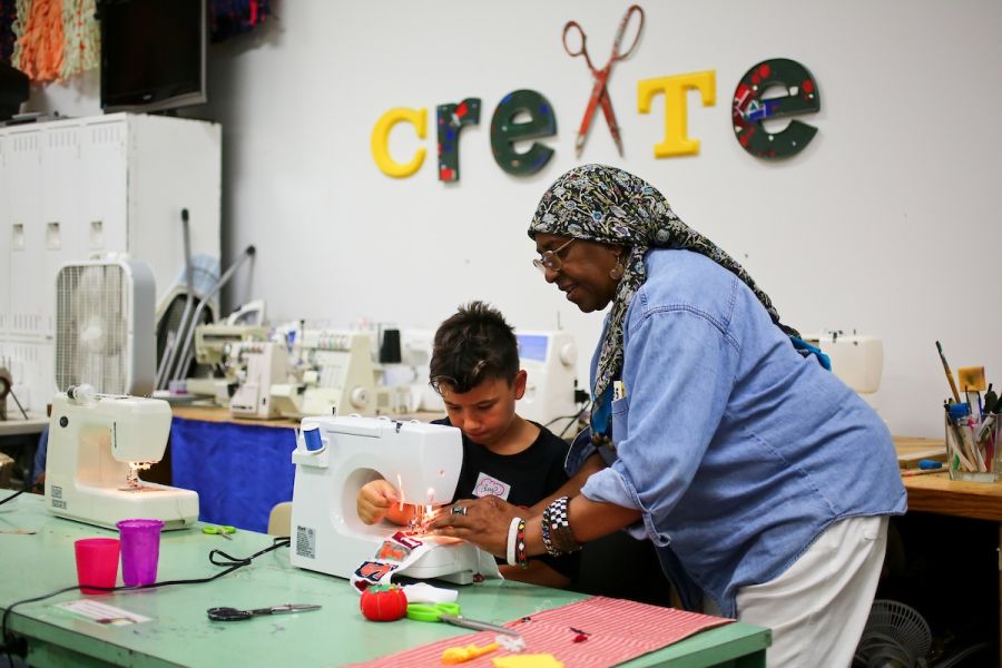 An employee at the Scrap Exchange helps a boy with a craft project.