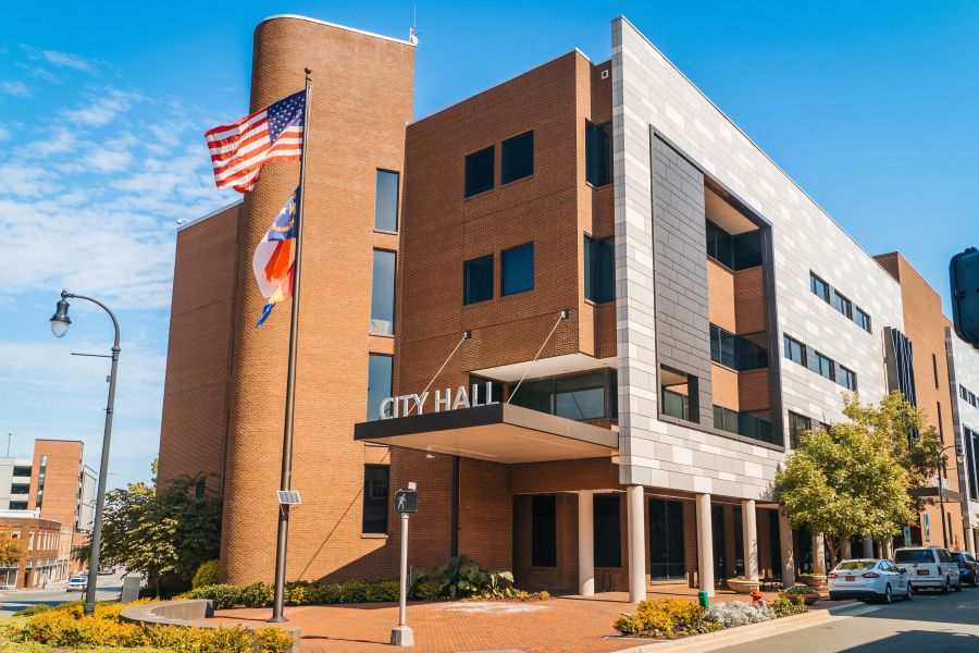 Durham City Hall stands tall under a blue sky with flags waving in the front.