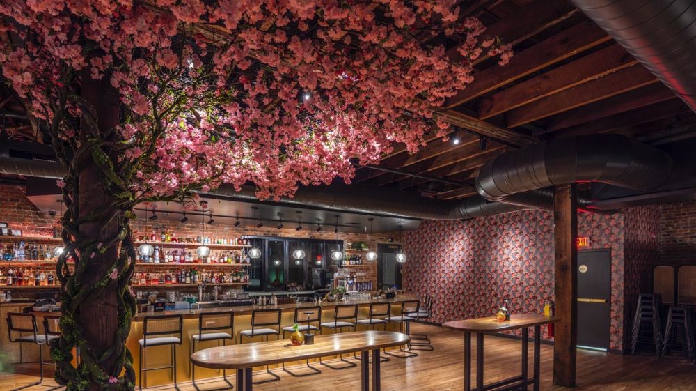 An artificial cherry trees boughs hang over the tables and bar at The Velvet Hippo in Durham, NC.