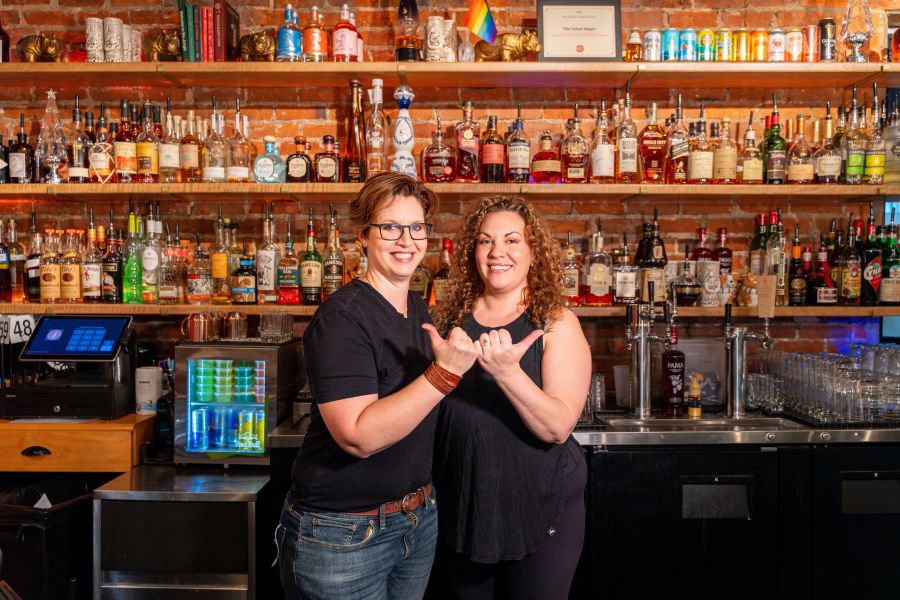 Two of the owners of The Velvet Hippo pose with the "Love Durham" bull horns in front of the bar.