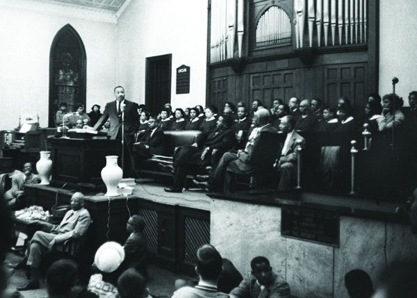 A black and white photo depicts Dr. Martin Luther King Jr. speaking at White Rock Baptist Church in Durham.