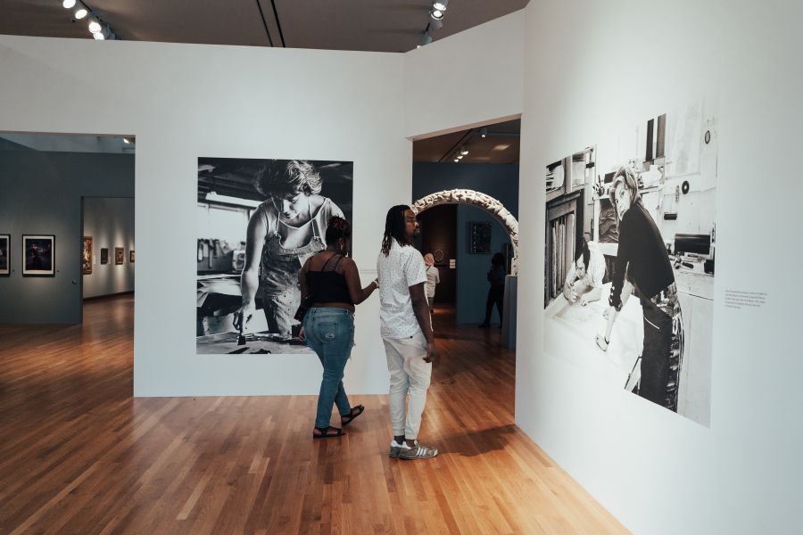 Two museum goers glance at photos as they pass through a doorway at the Nasher Museum in Durham.