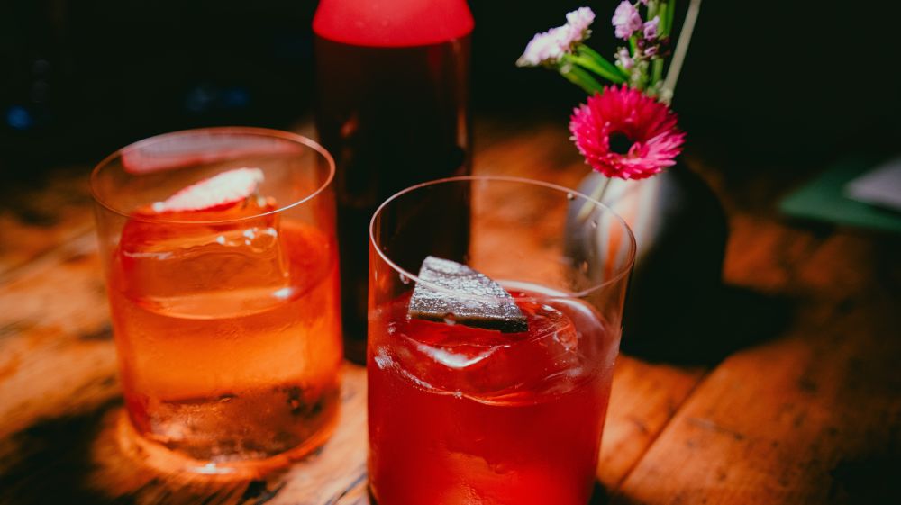 Amber colored cocktails sit on a dimly lit table at The Kingfisher in Durham, NC.