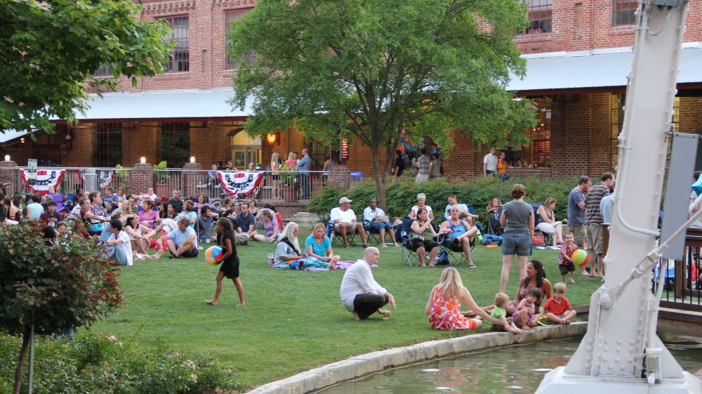 Visitors sit on the lawn at American Tobacco Campus in front of the man-made river.
