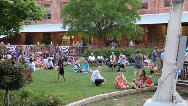 Visitors sit on the lawn at American Tobacco Campus in front of the man-made river.