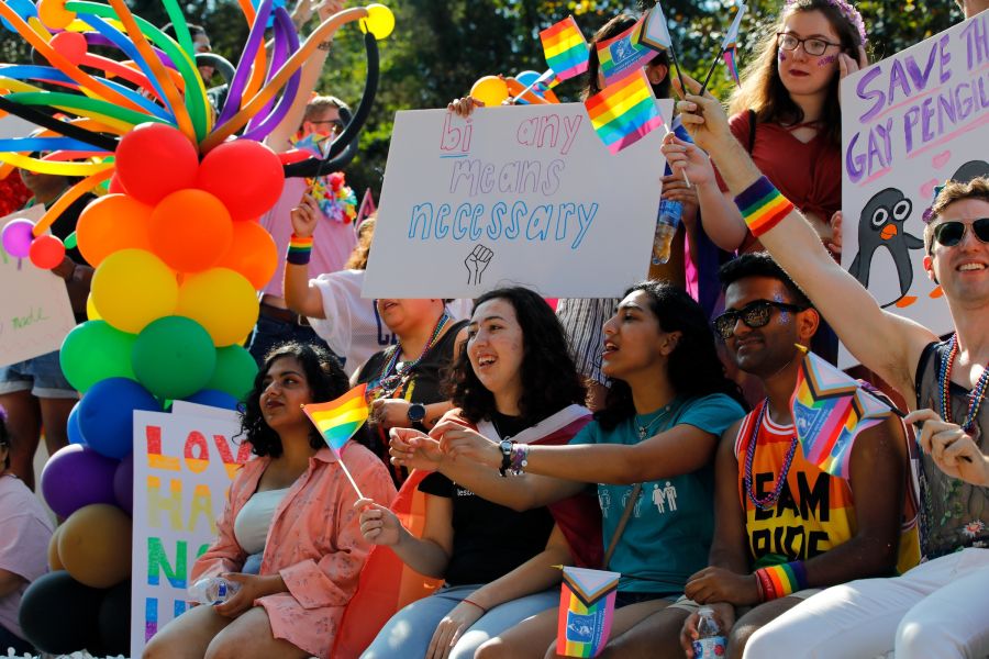 LGBTQIA residents and allies wave rainbow flags and hold up handmade signs on a colorful float at Pride: Durham, NC