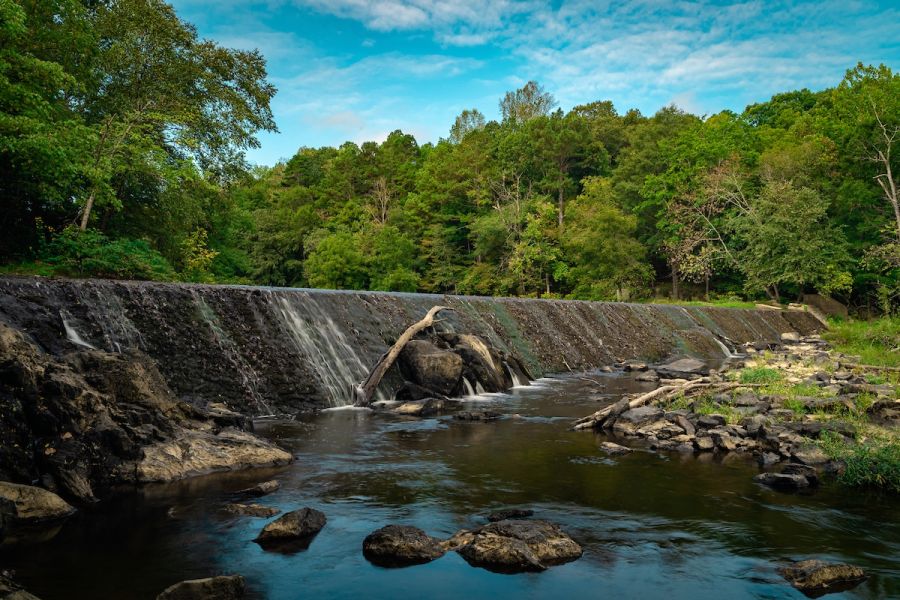 Water cascades over the dam at West Point on the Eno during a warm summer day.