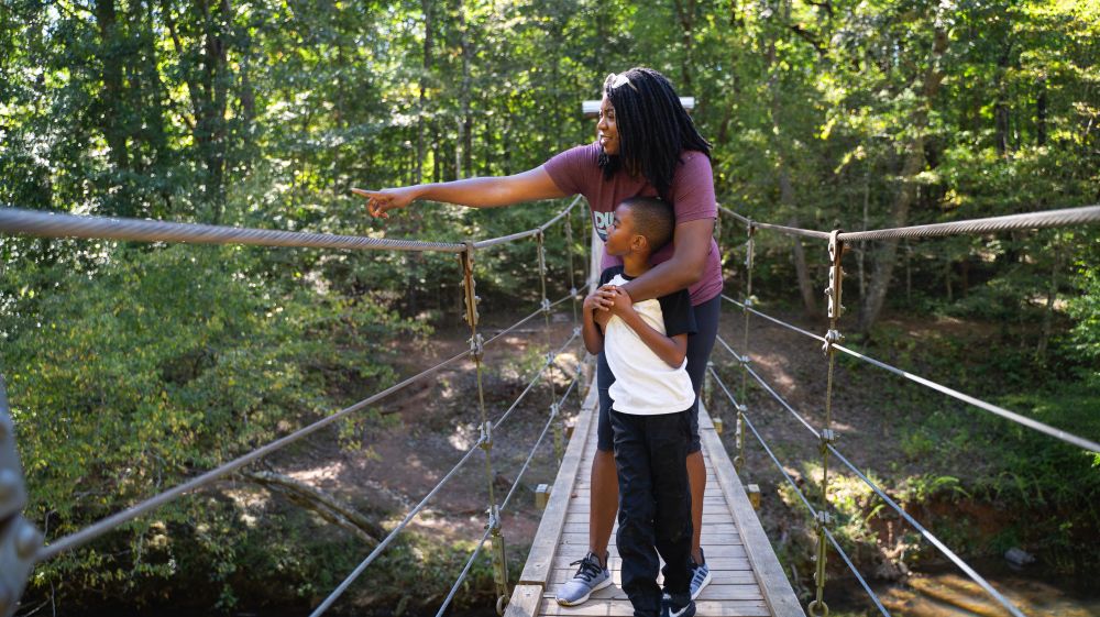 A mother and child view nature on the suspension bridge at Eno River State Park.